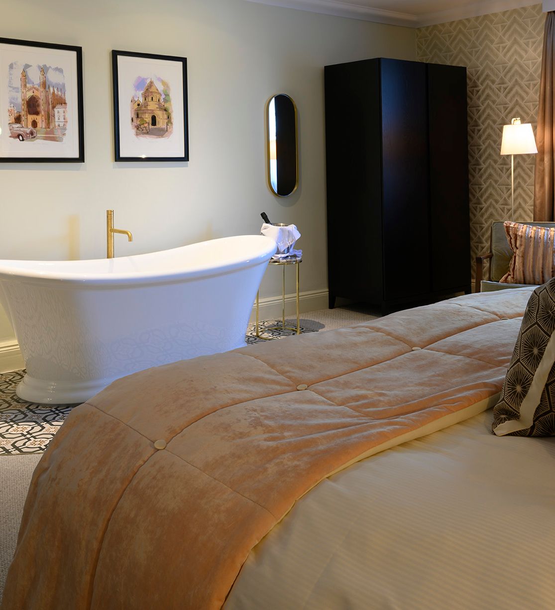 Elegant bedroom with a freestanding bathtub, plush bedding, modern decor, and natural light from a window.