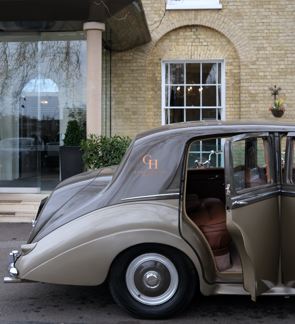Classic car parked in front of the Gonville Hotel entrance with an open rear door.