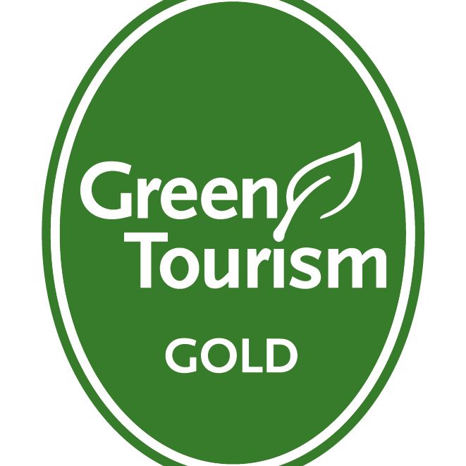 Green Tourism Gold award logo featuring a green oval with white text and a leaf symbol.