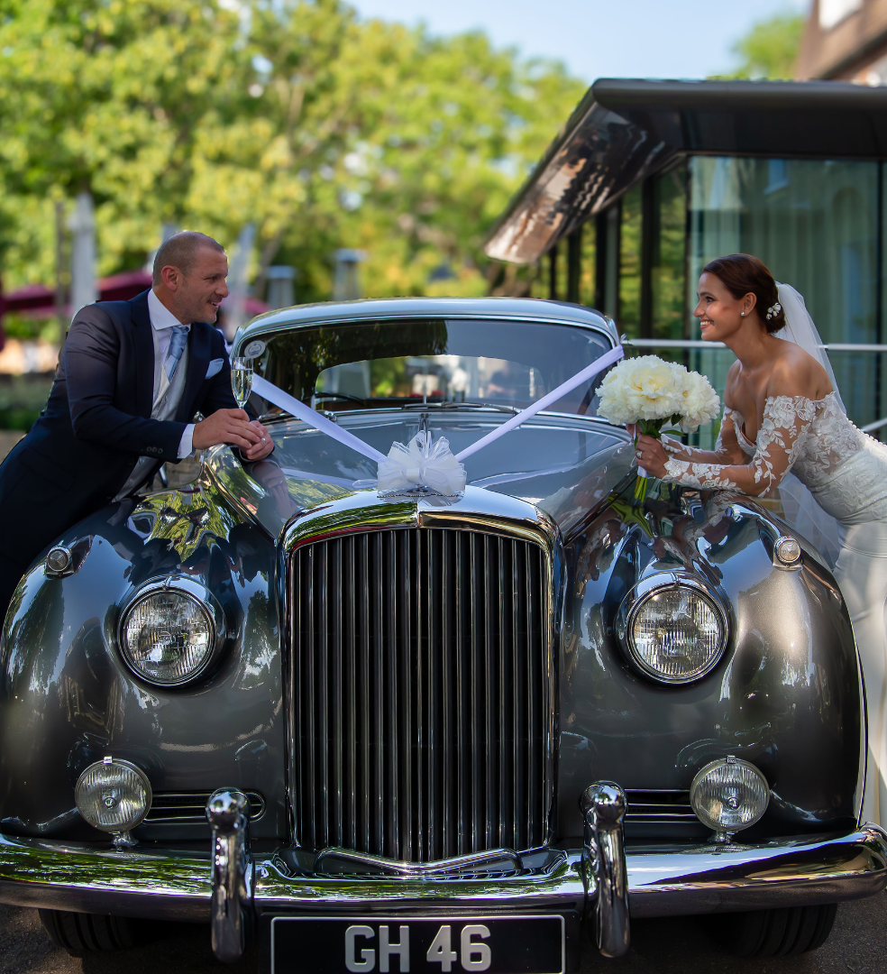 Bride and groom posing with a decorated vintage car