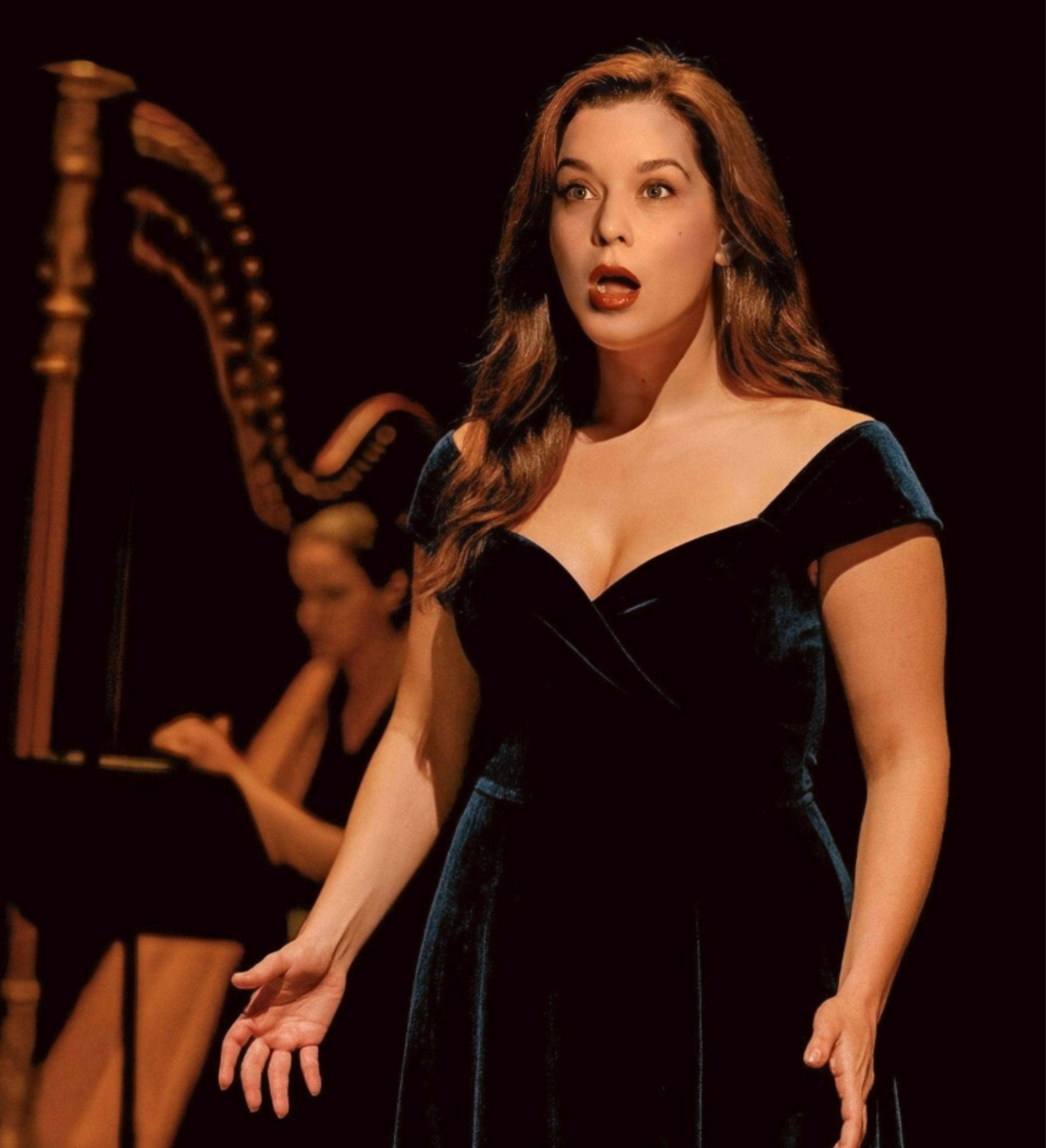Opera singer performing on stage with a harpist in the background