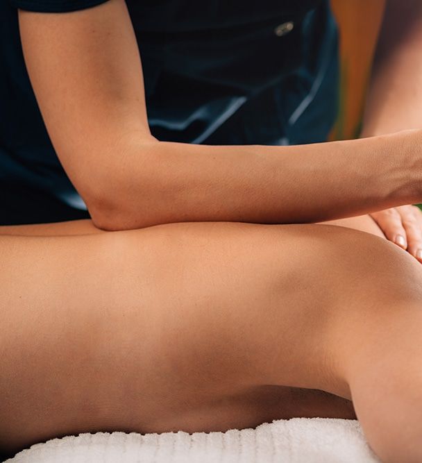 Massage therapist performing a deep tissue back massage on a client lying face down on a towel