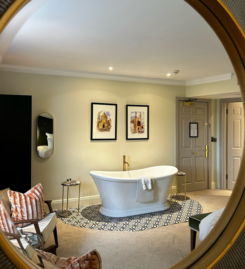 Luxury hotel suite with freestanding bath reflected in a round mirror