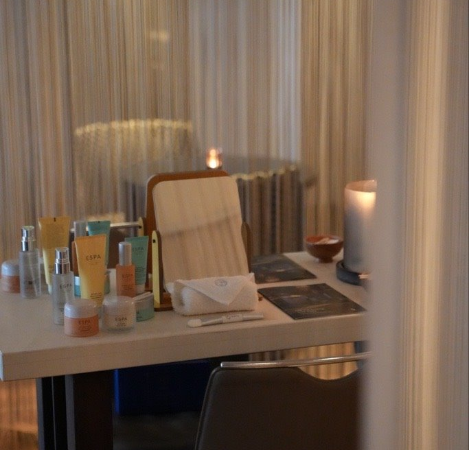 Table set up for a skincare masterclass with ESPA products, mirror and candle in a softly lit room