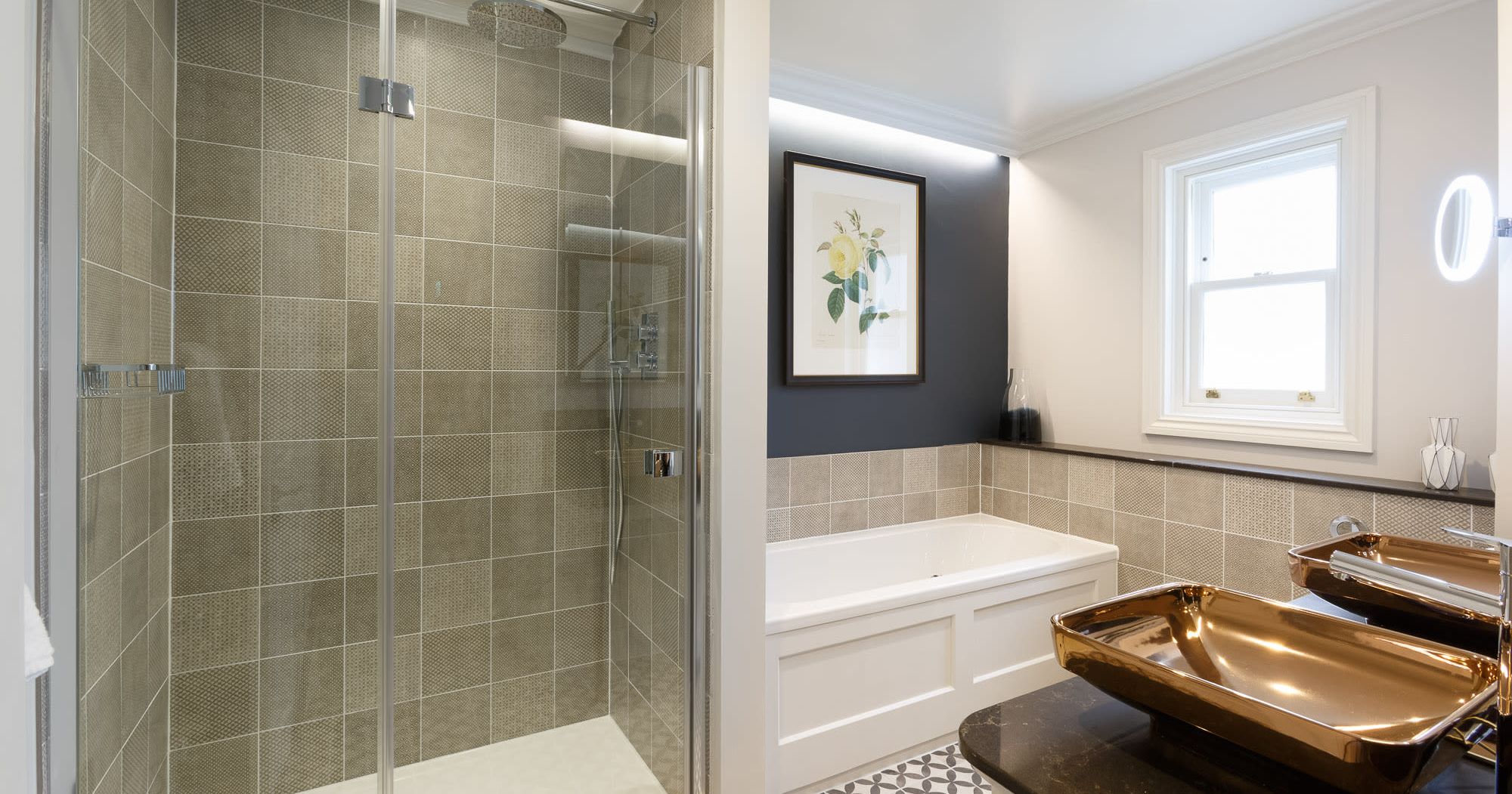 The bathroom of the Rosa feature room at Gonville Hotel, featuring a walk-in shower, deep bathtub, gold basin sinks, and elegant modern decor.