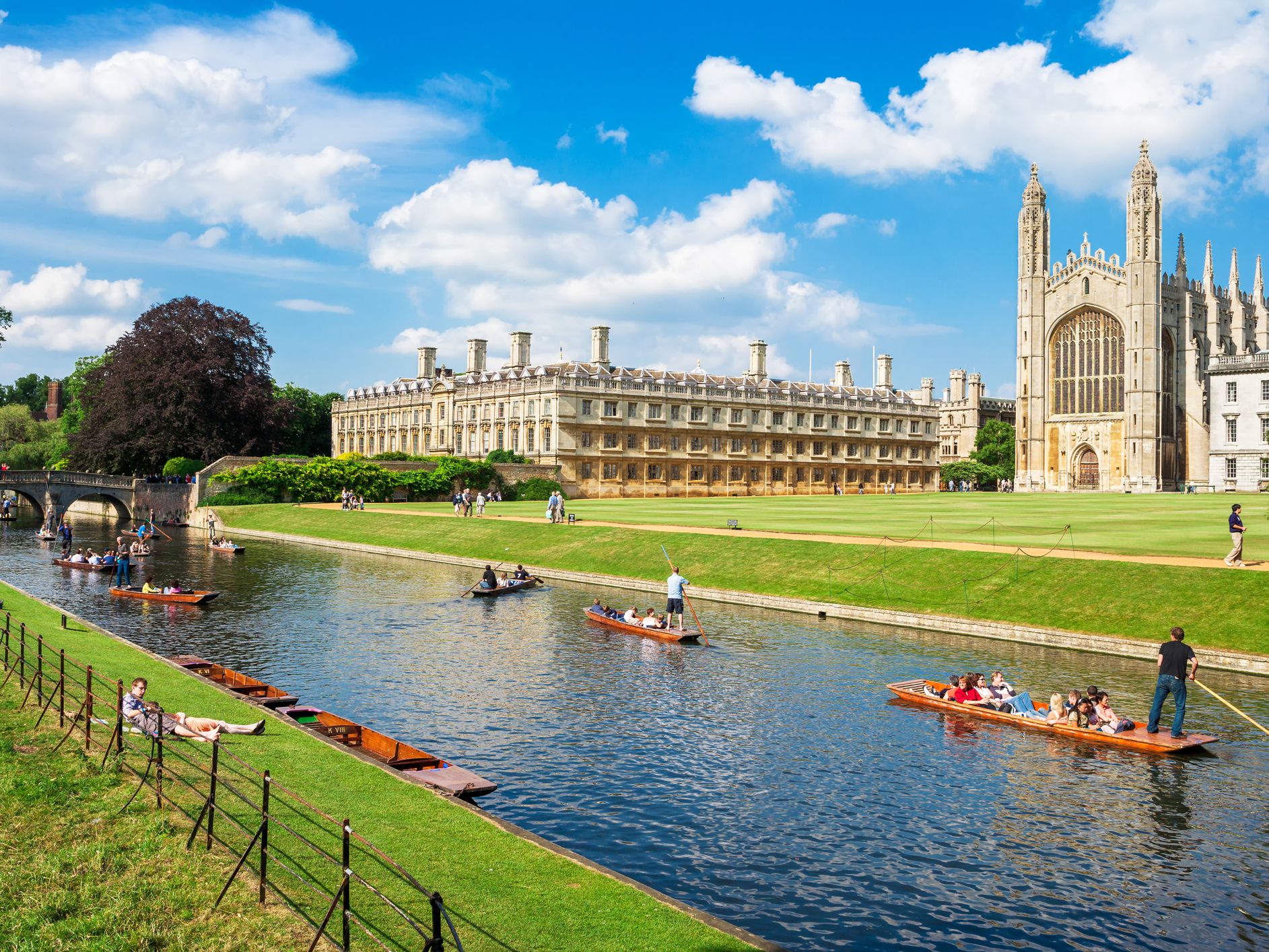Scenic view of punting on the River Cam in Cambridge, with historic college buildings and lush green lawns, a popular setting for events in Cambridge under a bright blue sky.