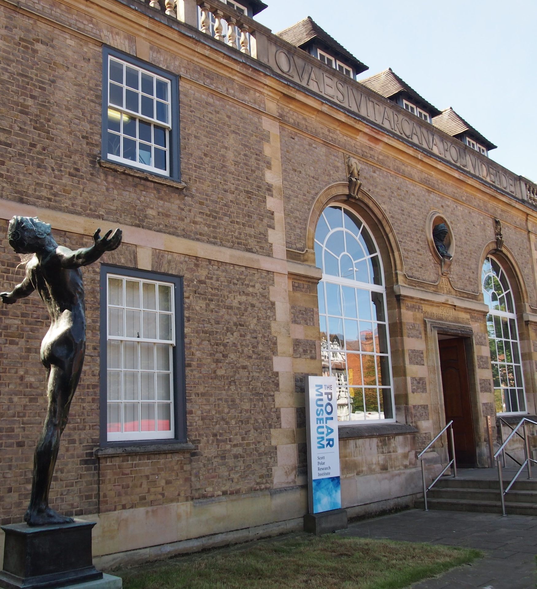 Exterior view of the Scott Polar Research Institute with a bronze statue outside.