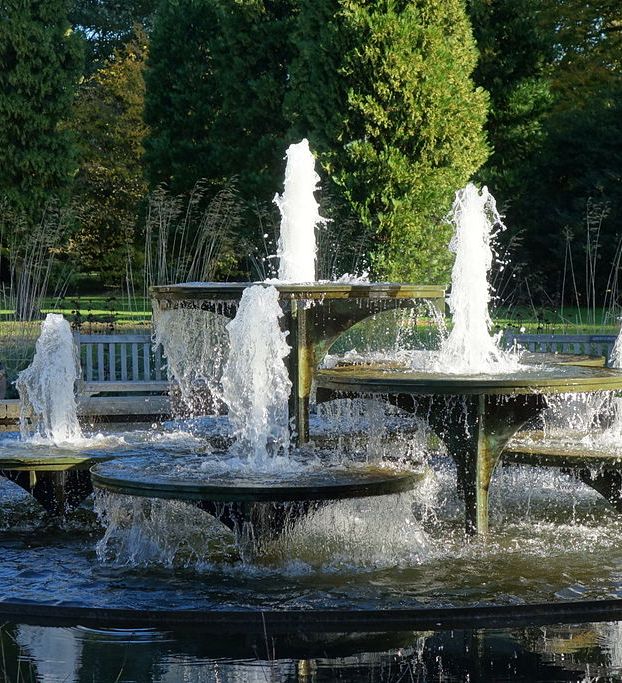 Tiered water fountain with multiple streams in a botanical garden setting