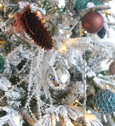 Close-up of a decorated, snow-frosted Christmas tree with ornaments and pinecones