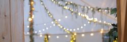 Decorated event tent with string lights, wooden furniture, and greenery.