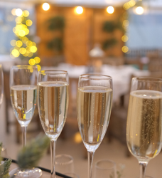 Close-up of champagne glasses with bubbles, blurred festive lights in the background