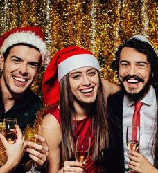Group of friends wearing Santa hats celebrating a Christmas party with champagne