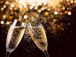 Two champagne glasses clinking with golden sparkling lights in the background