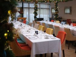 Elegant atrium dining area decorated for a festive event with colorful chairs and white tablecloths.