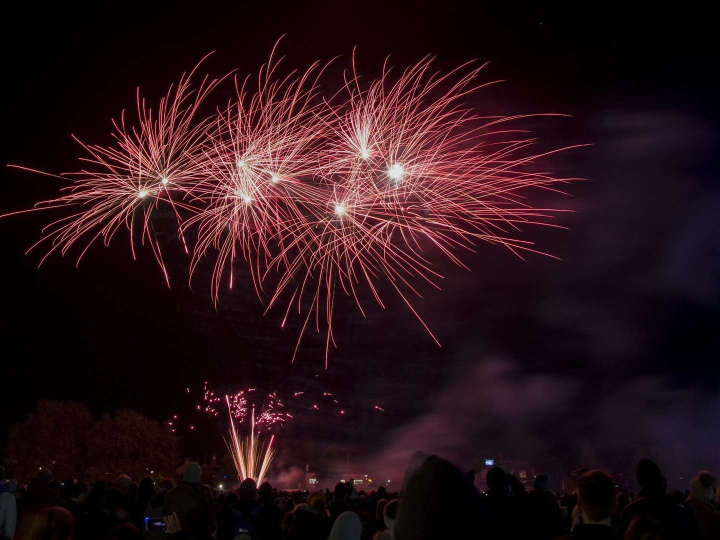 Fireworks display lighting up the night sky above a crowd of people