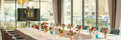 Elegant meeting room at Gonville Hotel Cambridge with U-shaped table setup, floral centerpieces, and large windows.