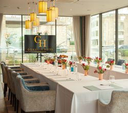Elegant meeting room at Gonville Hotel Cambridge with U-shaped table setup, floral centerpieces, and large windows.