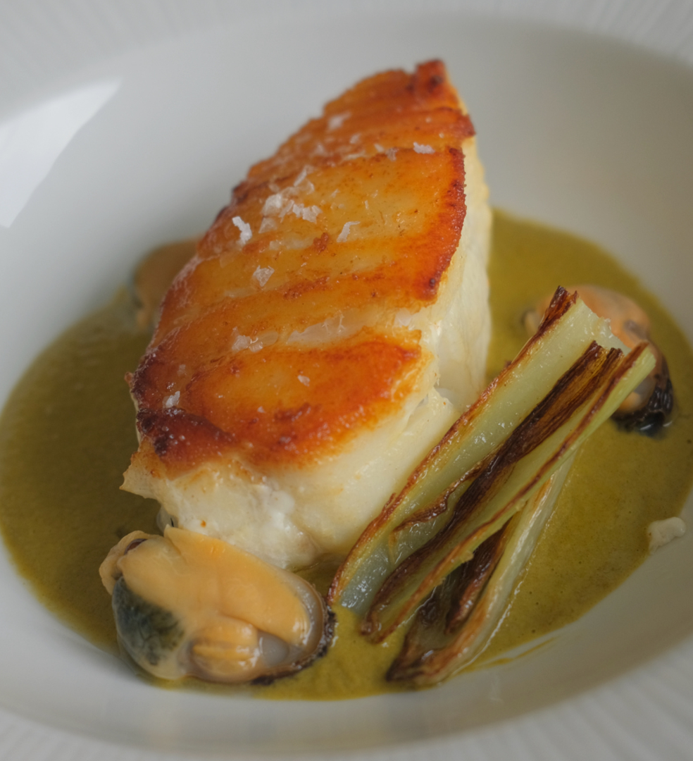 Seared fish fillet with mussels and charred leeks in a green sauce