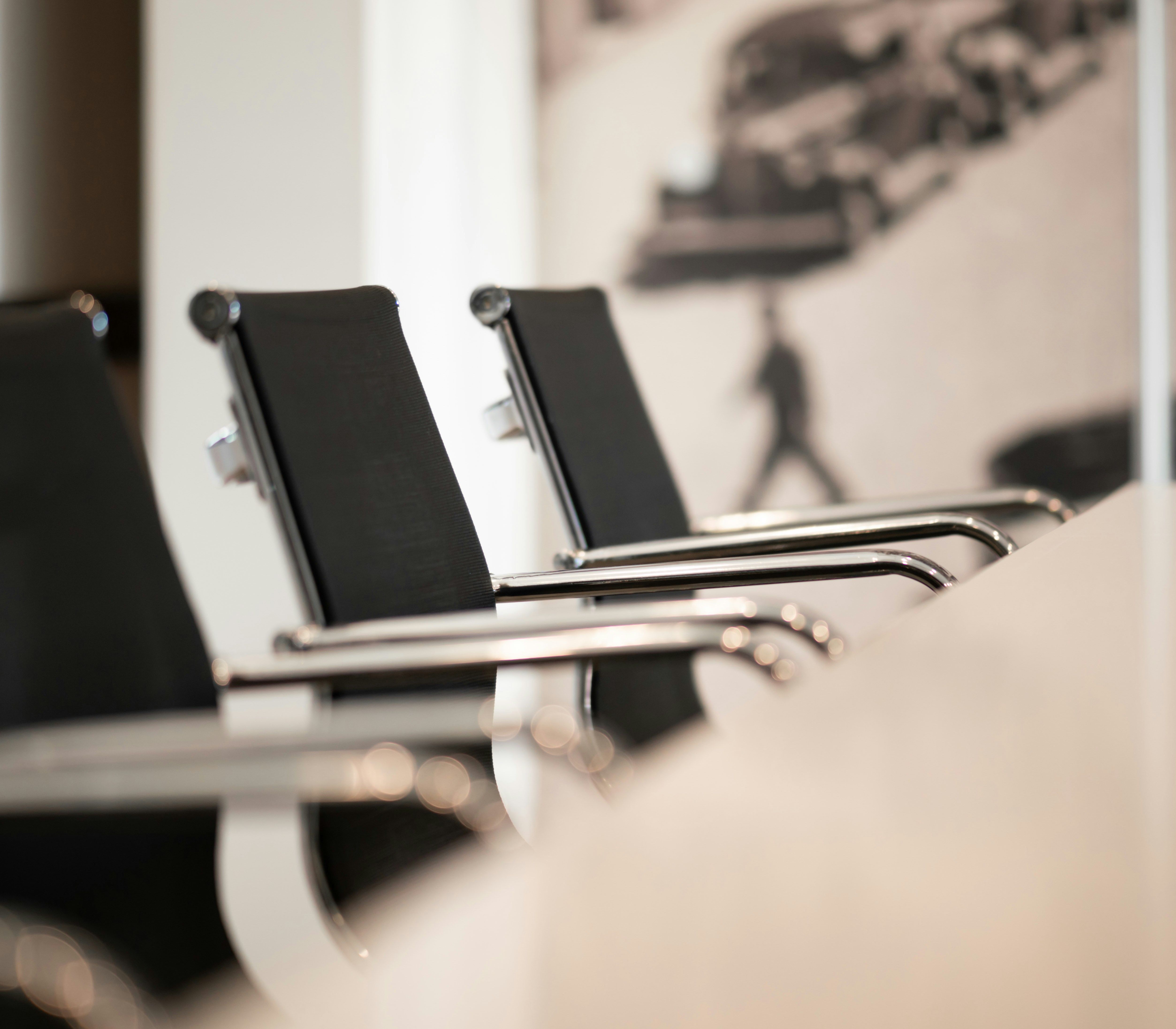 Empty modern office chairs around a conference table with a blurred background.