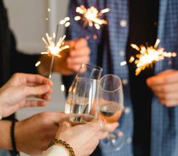 Group of people holding sparklers and clinking glasses in a celebration