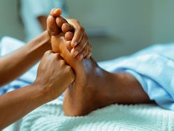 Close-up of a person receiving a foot massage, with hands applying pressure to the sole of the foot.