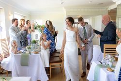 Bride and groom entering a wedding reception as guests applaud