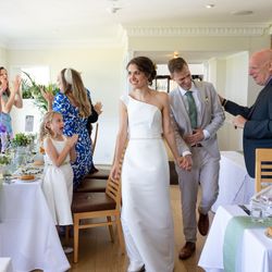 Bride and groom entering a wedding reception as guests applaud