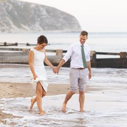 Bride and groom walking barefoot on the beach near the sea