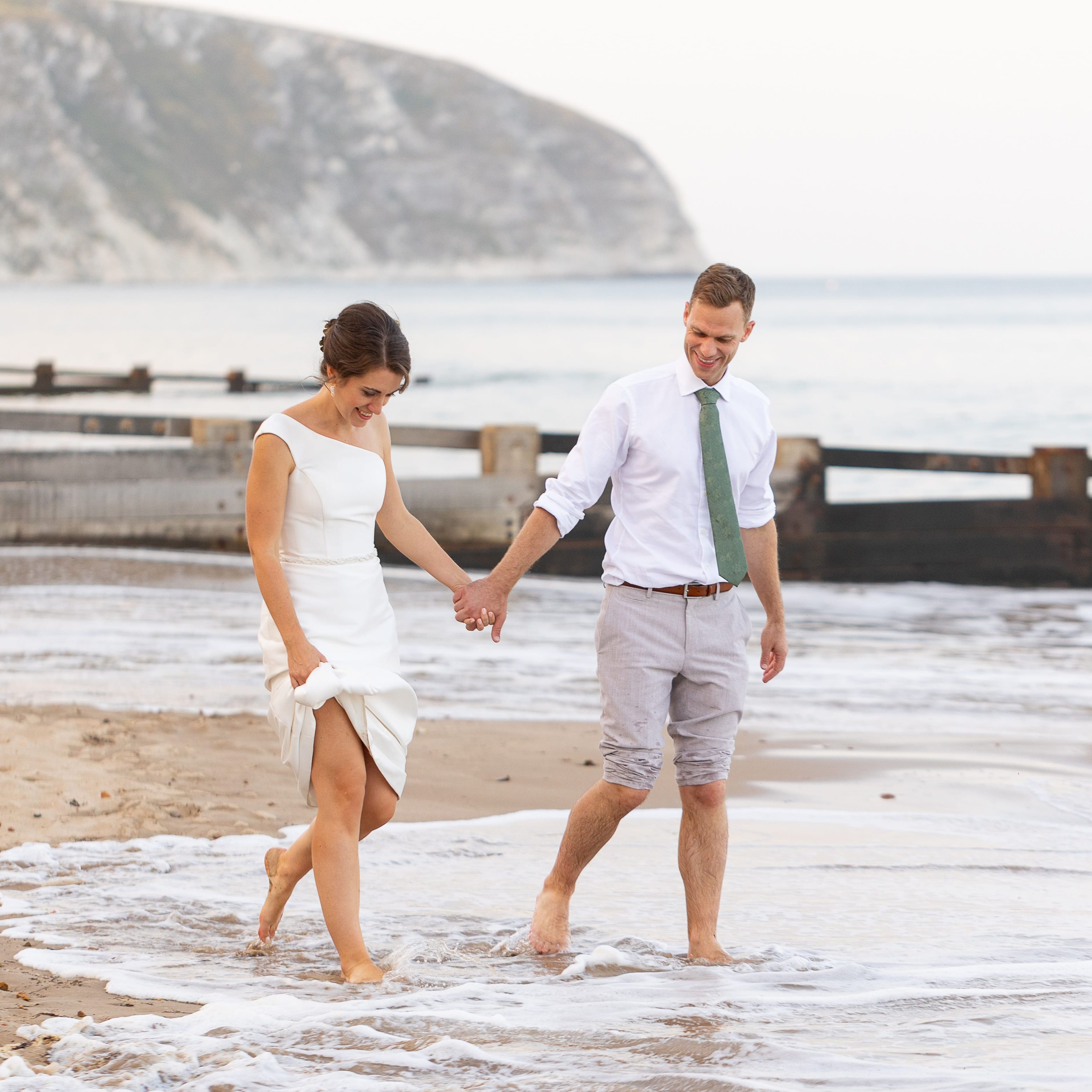 Bride and groom walking barefoot on the beach near the sea