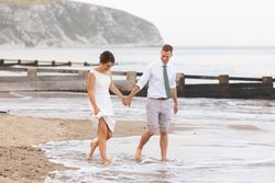 Bride and groom walking barefoot on the beach near the sea