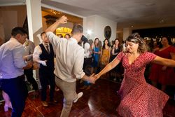 People dancing at an indoor party, with a woman in a red polka dot dress spinning on the dance floor.