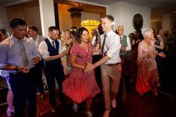 Group of people dancing at a lively indoor party or wedding reception.