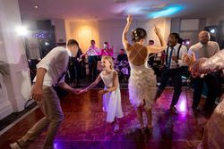 People dancing and celebrating at a wedding reception with a live band in the background.