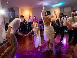 People dancing and celebrating at a wedding reception with a live band in the background.