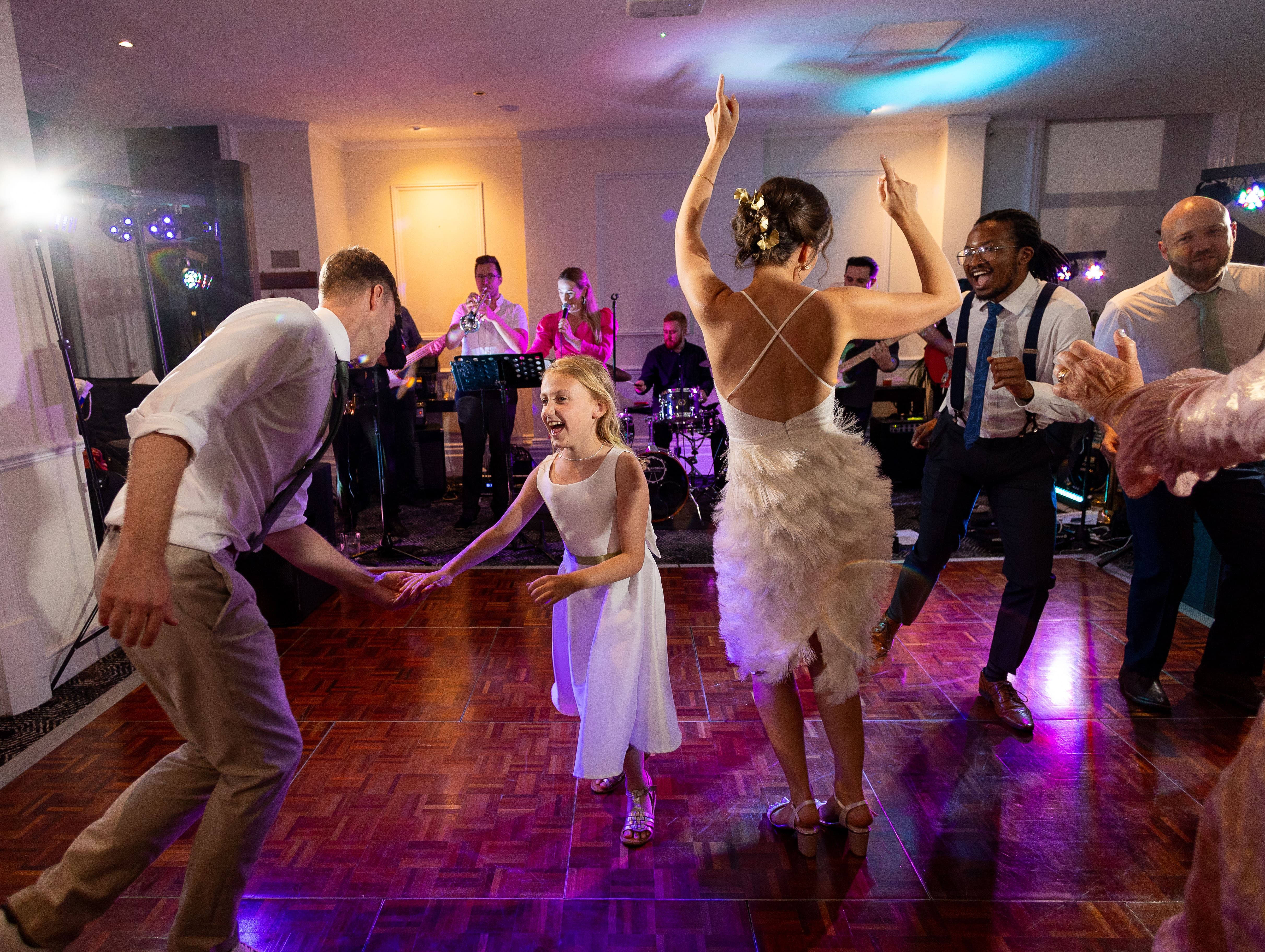 People dancing and celebrating at a wedding reception with a live band in the background.