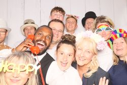 A group of people wearing fun hats and costume accessories smiling together in a photo booth.
