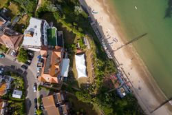 Aerial view of a beach, nearby buildings, roads, and a tented area next to the sand.