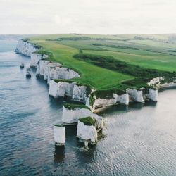 Aerial view of white chalk cliffs along a coastline with green fields above