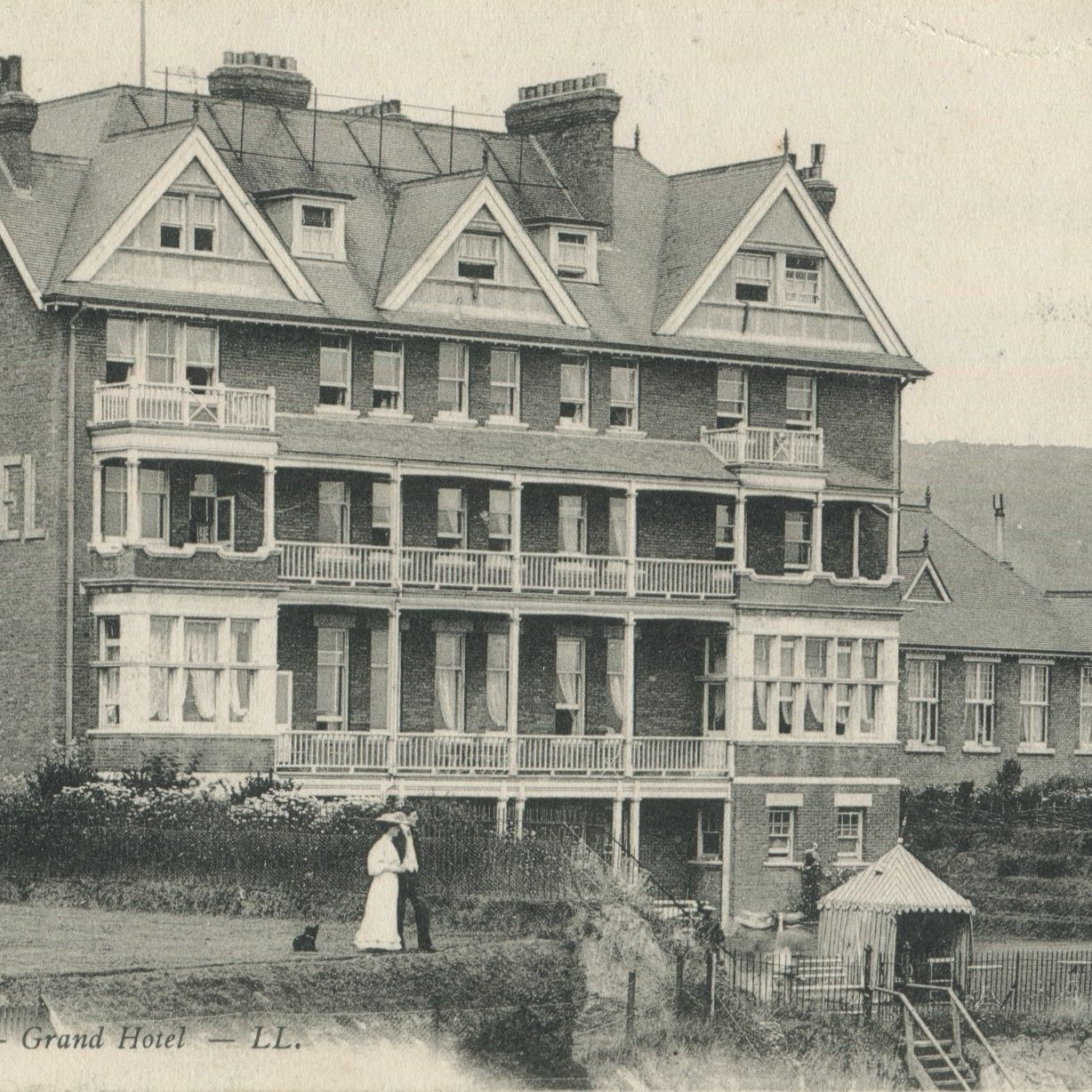 Vintage photograph of the Grand Hotel in Swanage with two people standing in front of the building.