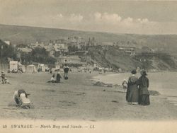 Vintage photograph of Swanage North Bay and Sands, showing people on the beach with cliffs and seaside buildings in the background.