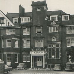 Vintage photograph of the Grand Hotel in Swanage, England, showing the building's exterior facade with classic architecture and parked cars in front.