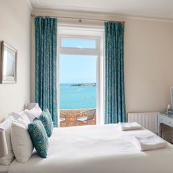Cozy bedroom with a large window offering a scenic ocean view.