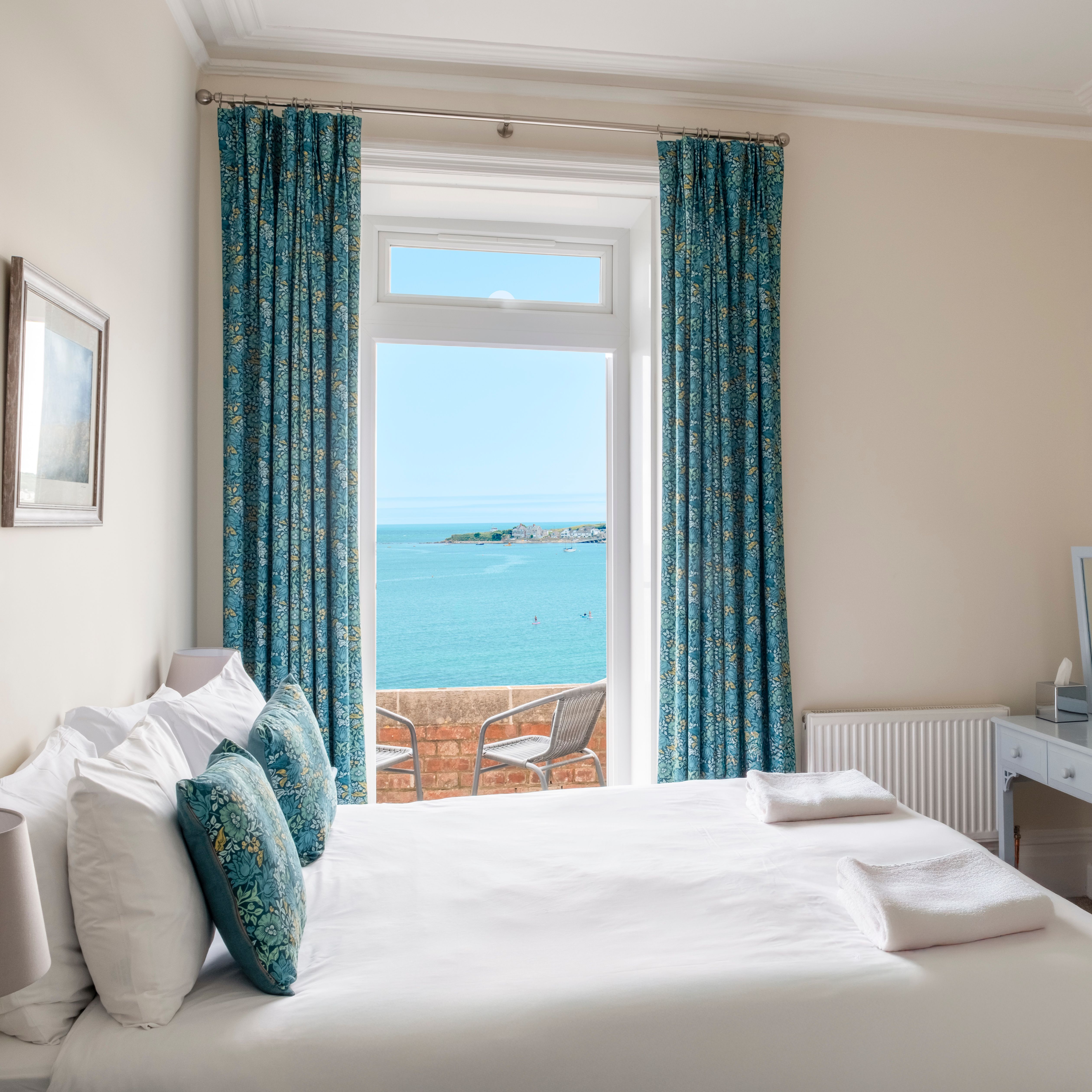 Cozy bedroom with a large window offering a scenic ocean view.