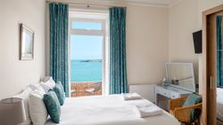 Cozy bedroom with a large window offering a scenic ocean view.