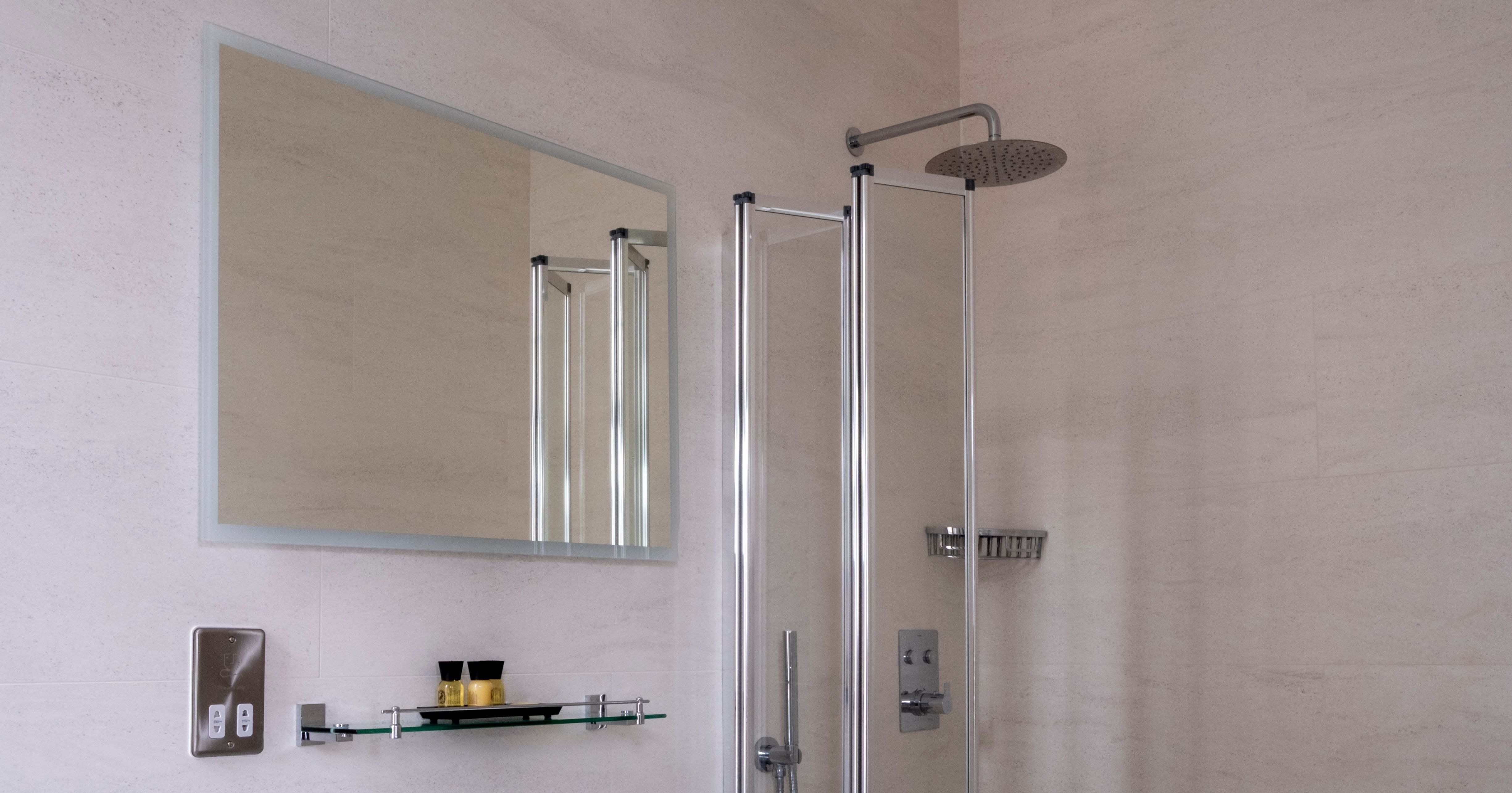 Modern bathroom with a white sink, wall-mounted mirror, glass shelf, bathtub with glass shower screen, and rainfall showerhead.