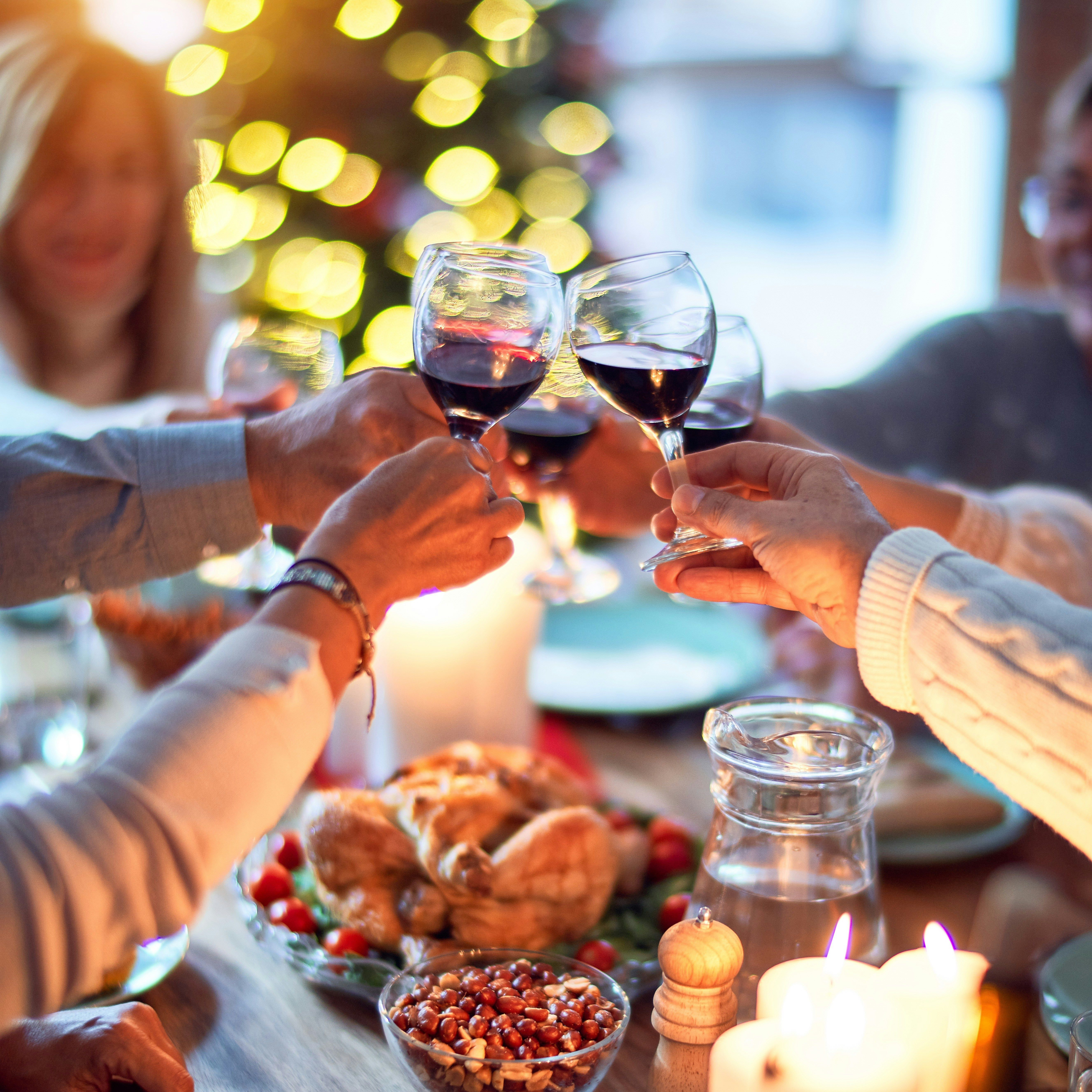 Group of people toasting with wine glasses at a festive dinner table.