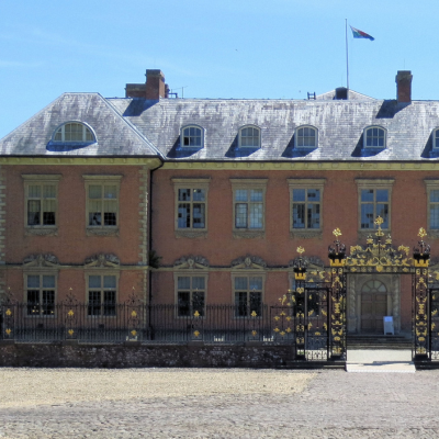 Ornate wrought-iron gate with gold detailing in front of a historic brick building