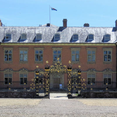 Ornate wrought-iron gate with gold detailing in front of a historic brick building
