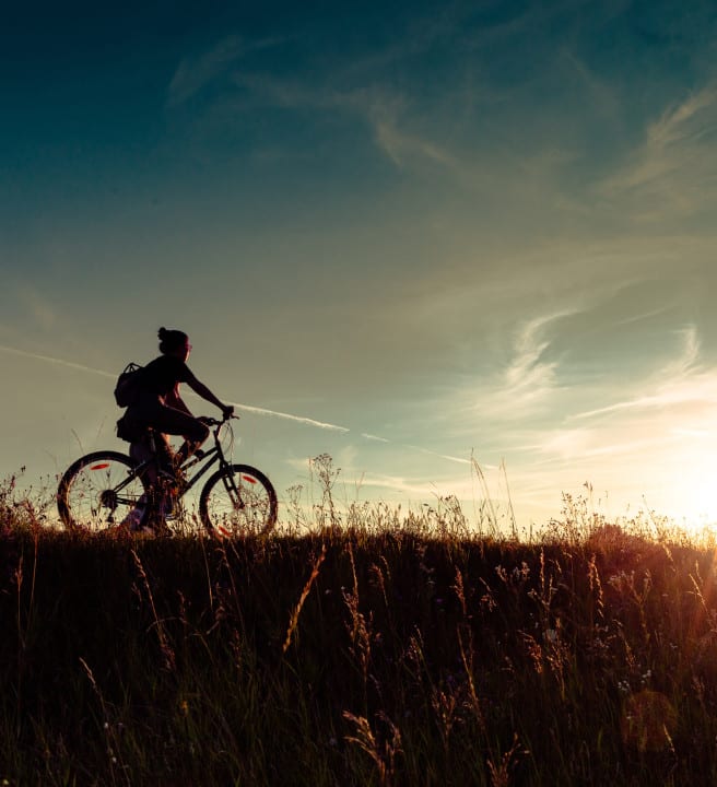 Person cycling whilst the sun sets