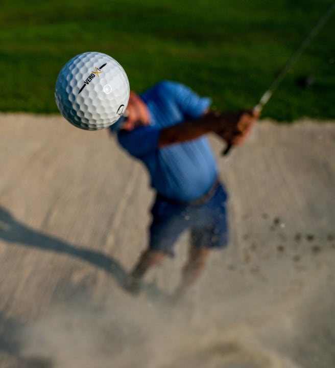 Man hitting a gold ball into the air